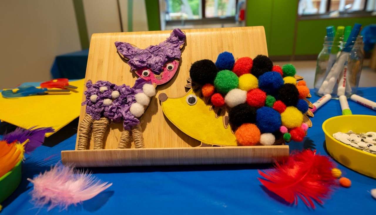 Wooden deer and hedgehog decorated with colourful craft materials.