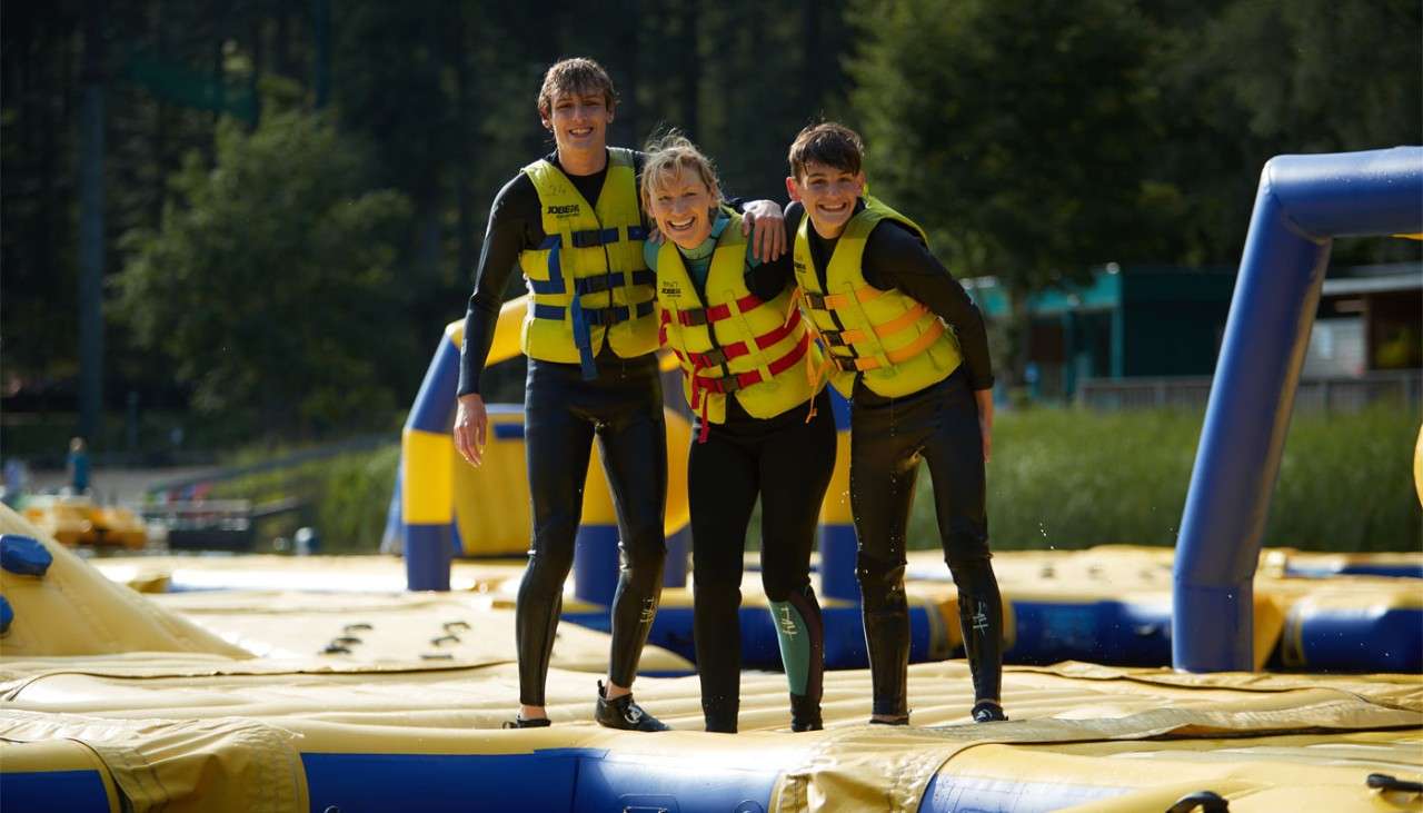 Family stood balanced on an inflatable obstacle course. 