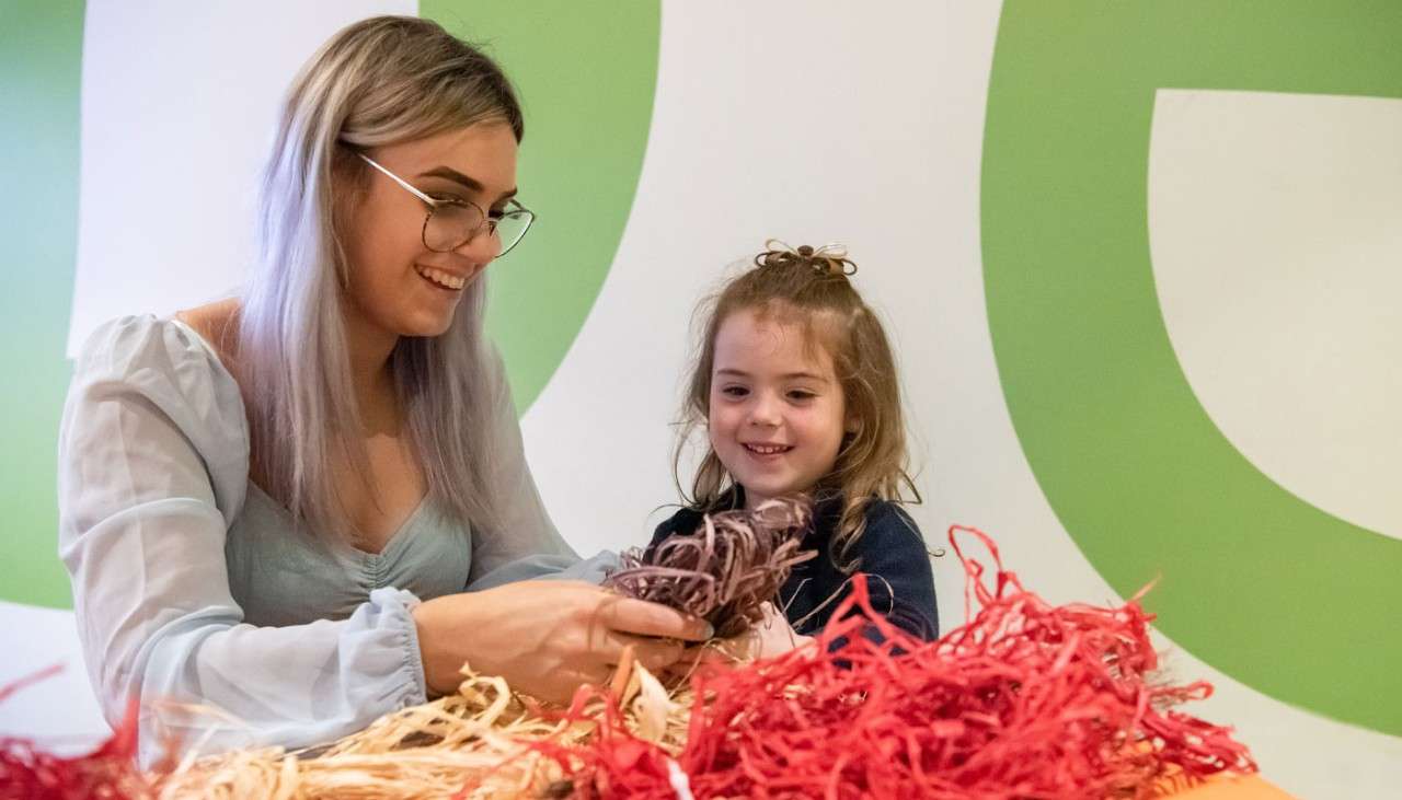 A woman and young girl making a Halloween craft