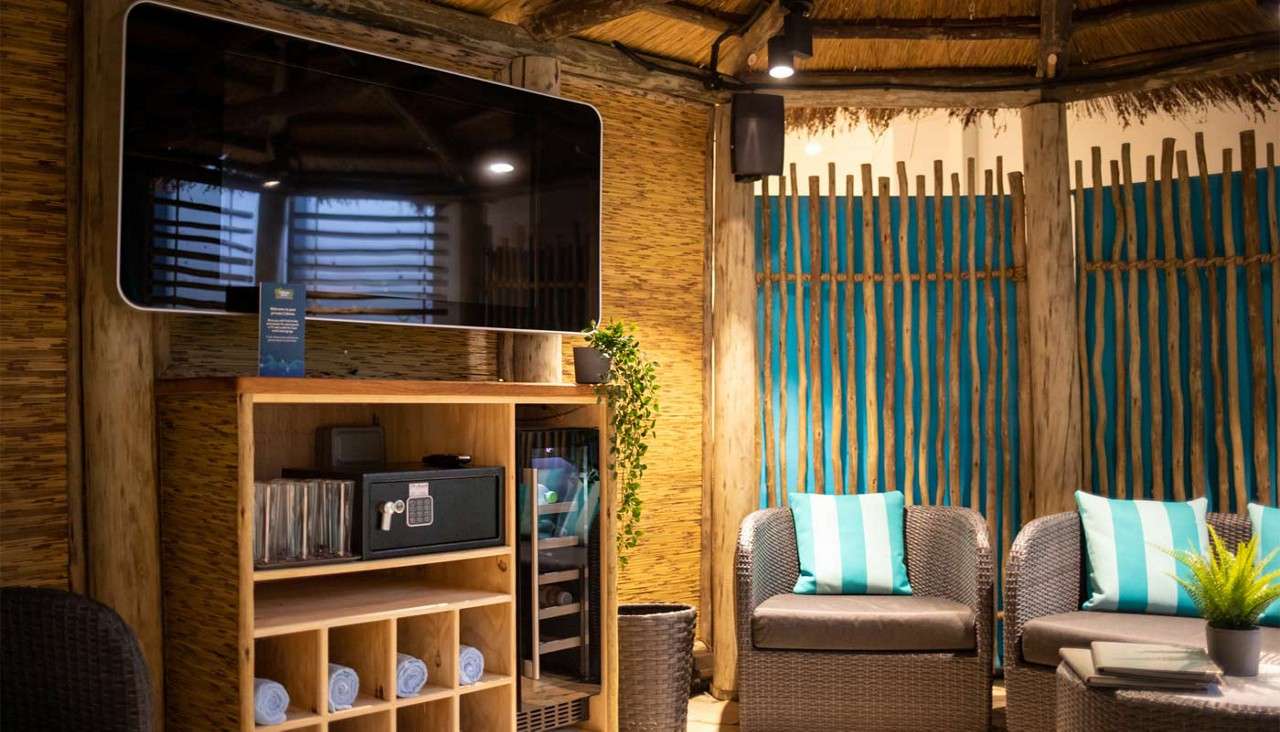 Cosy seating, fresh towels and a mounted TV inside the Exclusive Cabana Cove area.