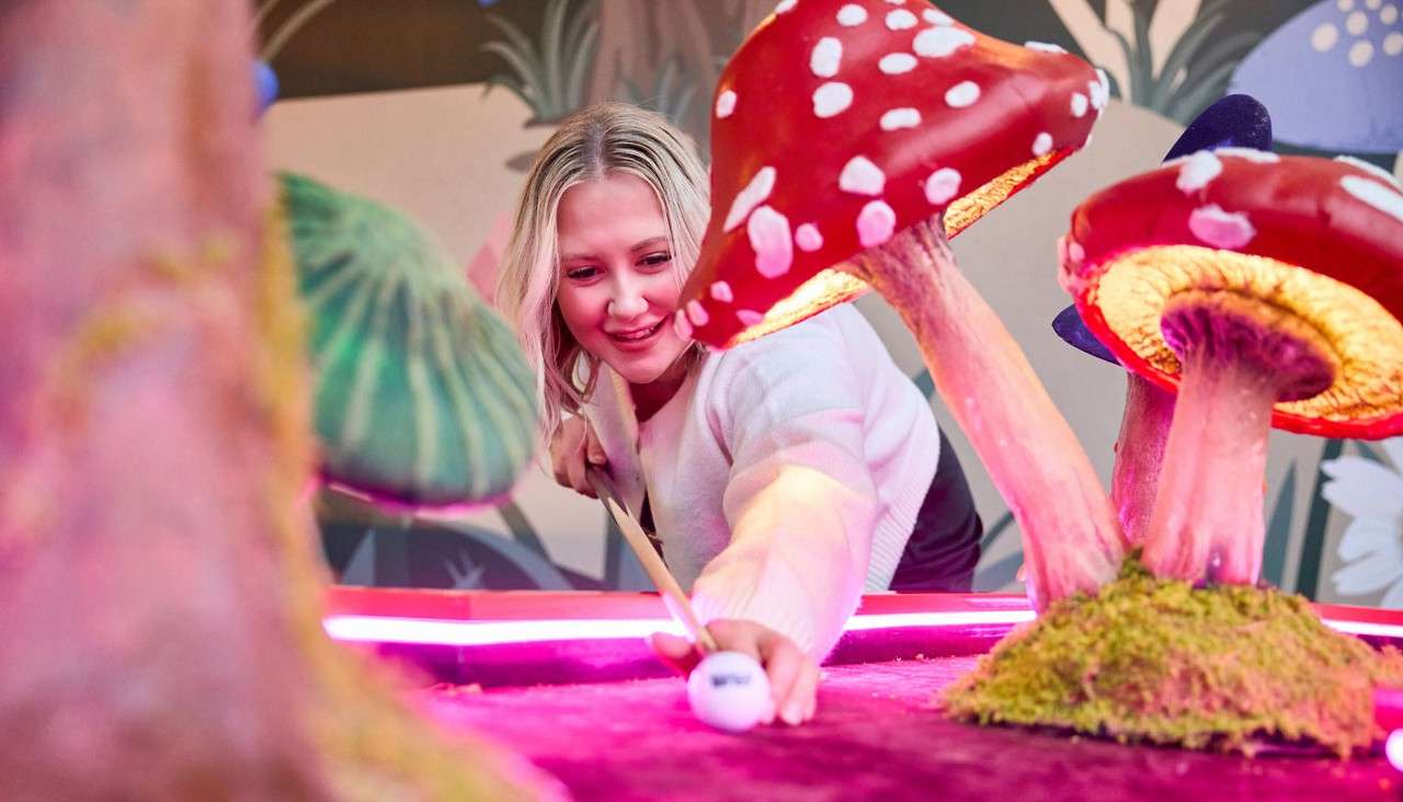 Two women playing Crazy Pool on a glowing table.