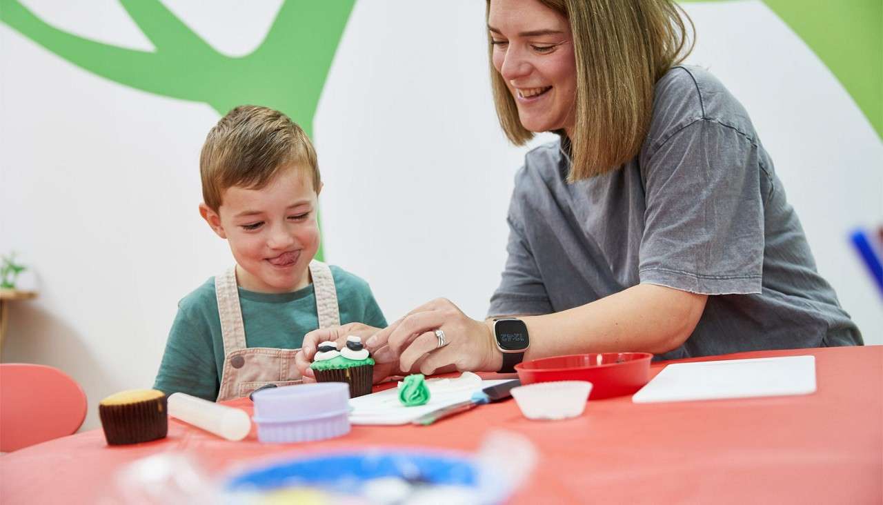 Woman and a young boy decorating cupcakes.