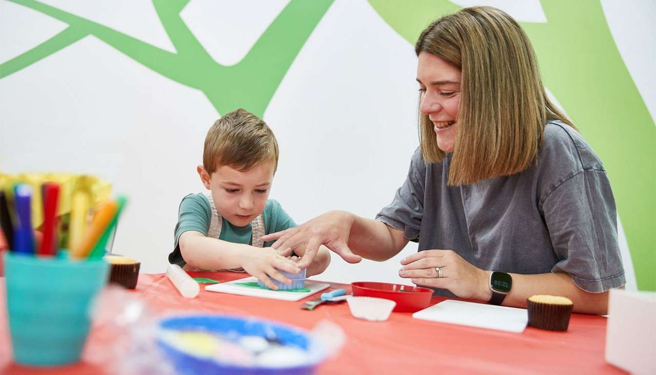 Woman and a young boy decorating cupcakes.