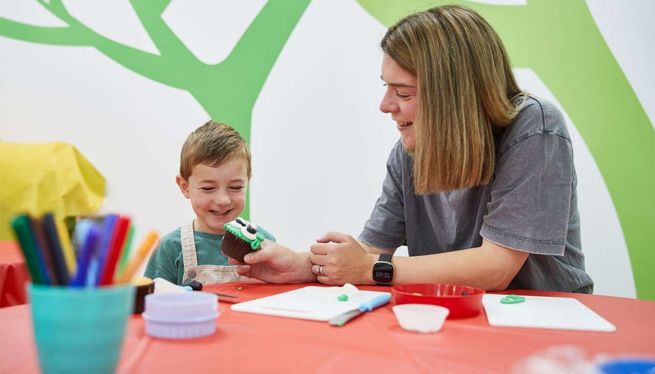 Woman and a young boy decorating cupcakes.