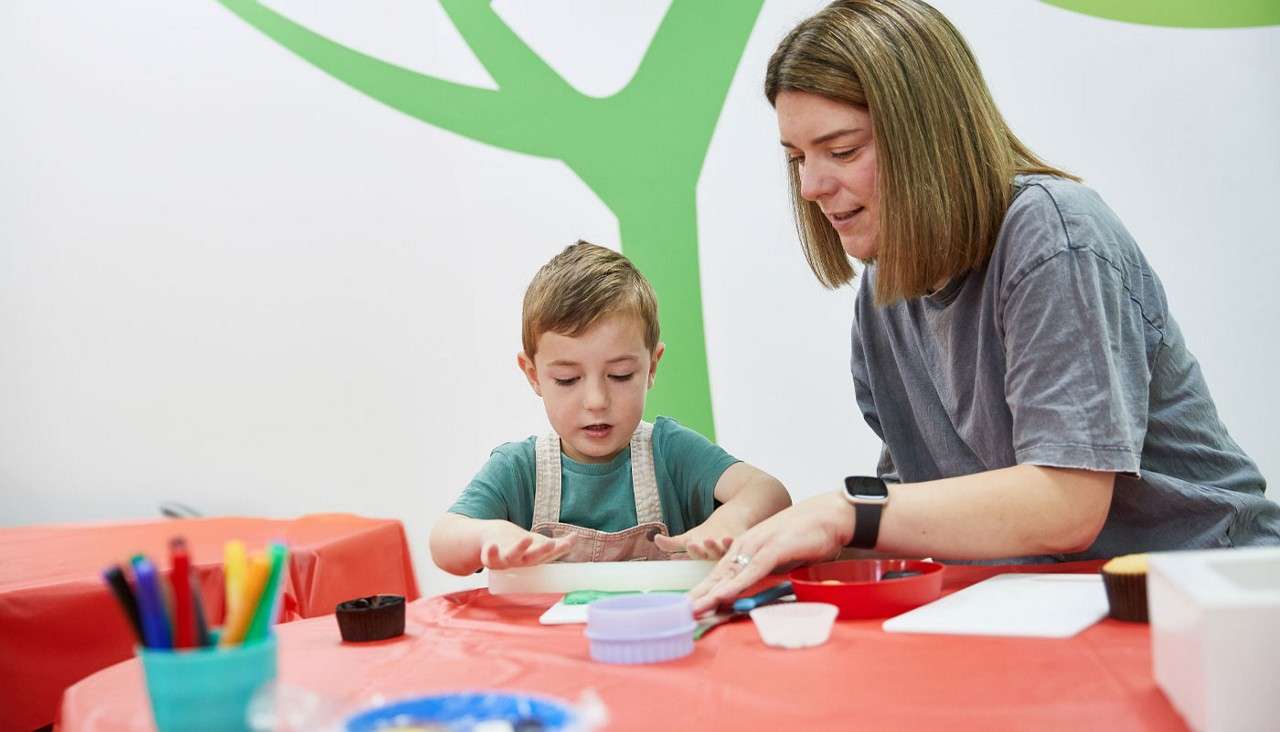 Woman and a young boy decorating cupcakes.