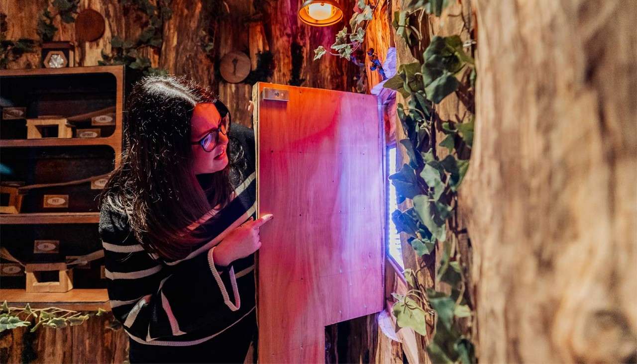 A woman opening a door to reveal a glowing light