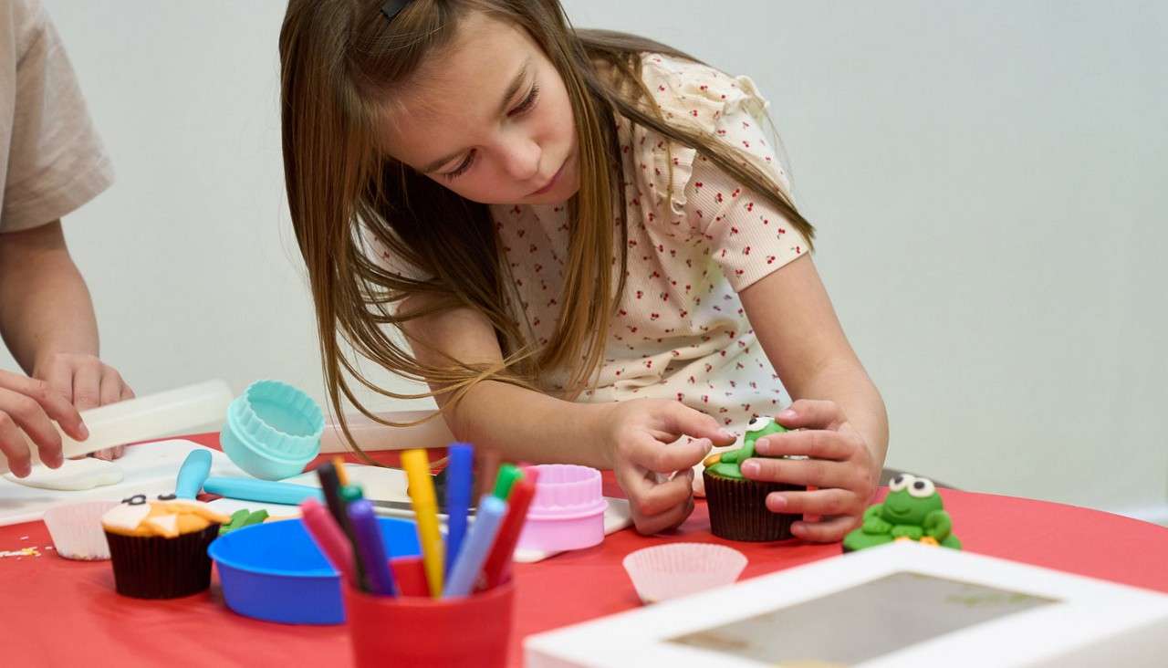 Girl decorating a cupcake.
