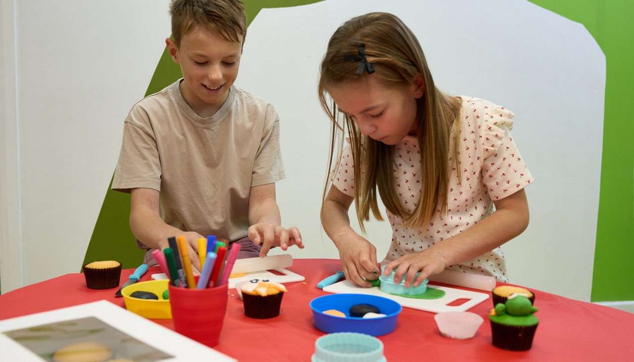 Two young people decorating cupcakes.