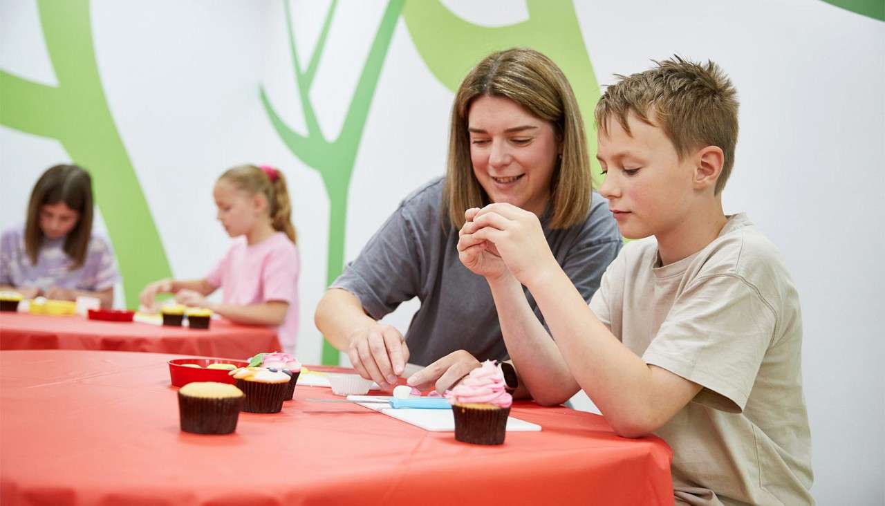 Two people decorating cupcakes.