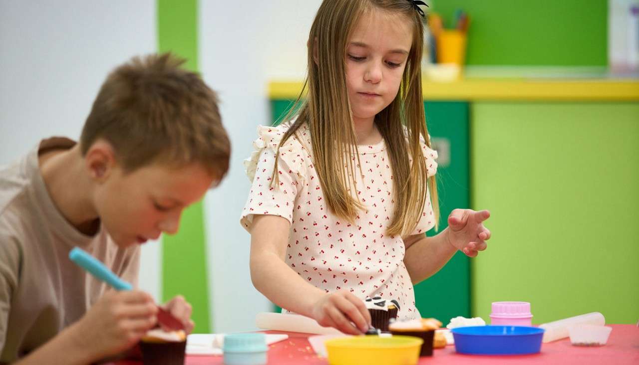 Two young people decorating cupcakes.