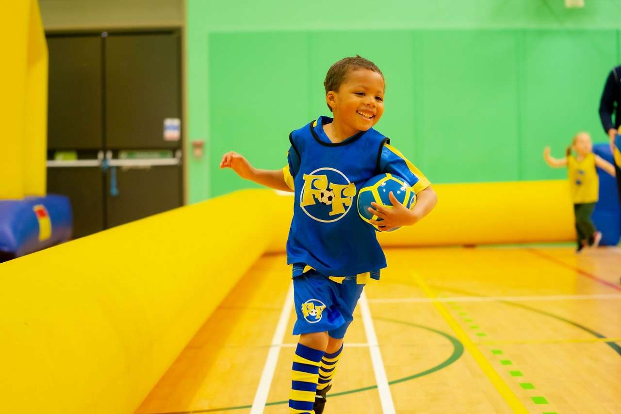 Young boy running with a football.