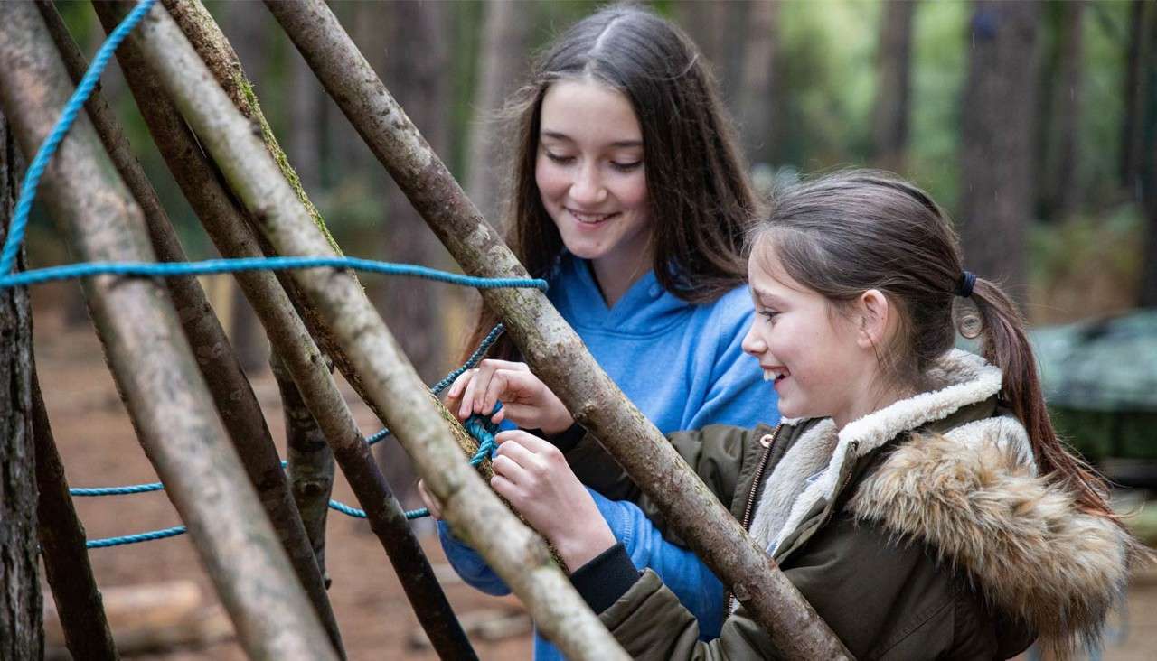 Two young children building a forest den