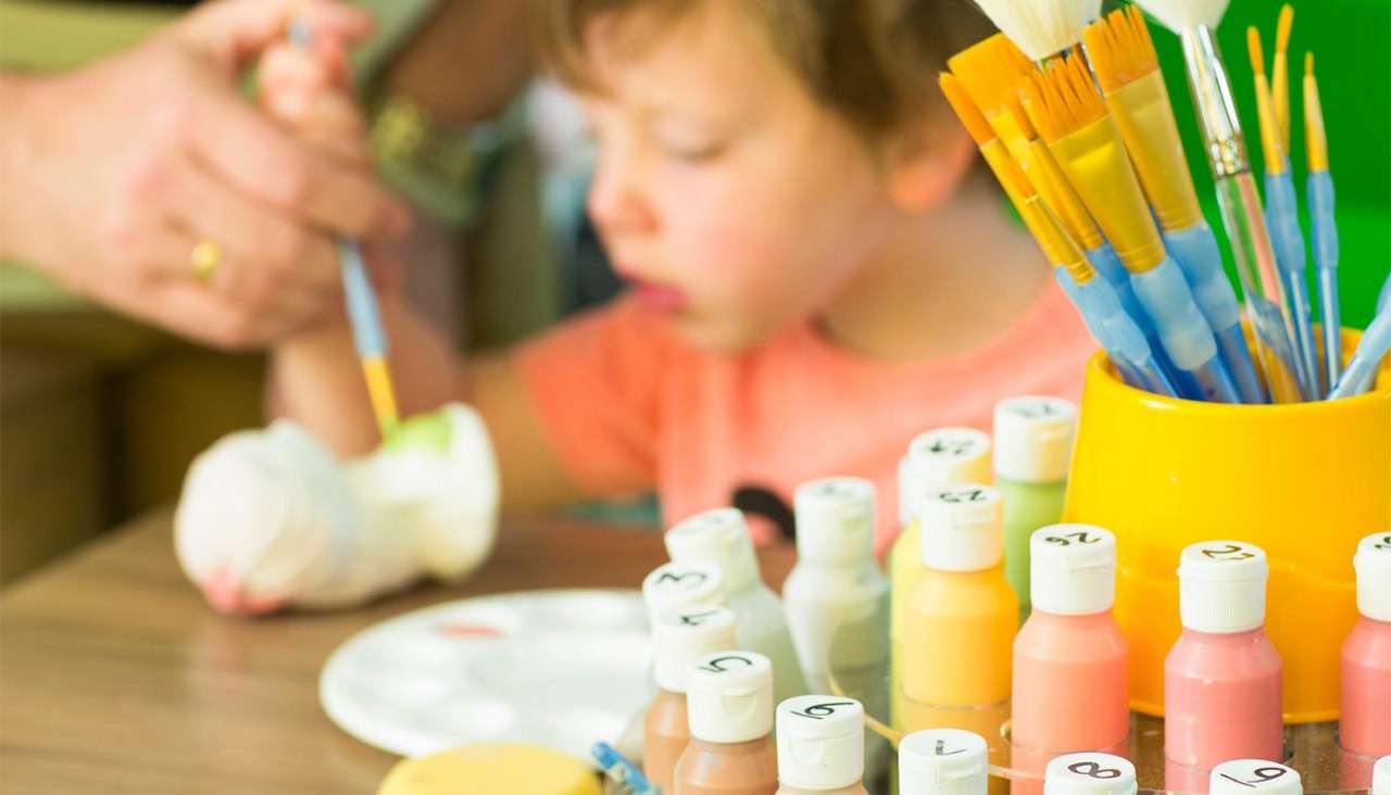 Young boy painting a piece of pottery