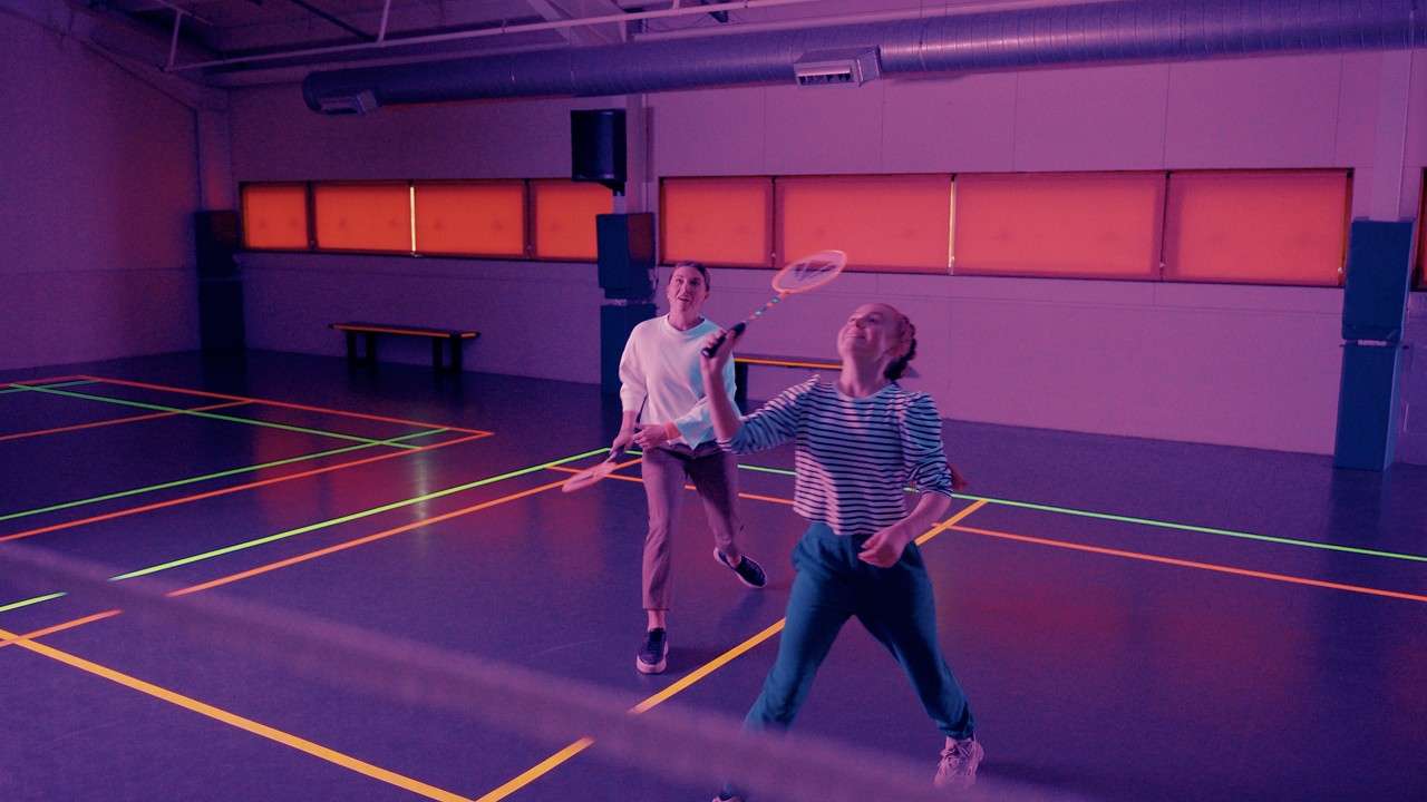 Family playing badminton with glow in the dark rackets.