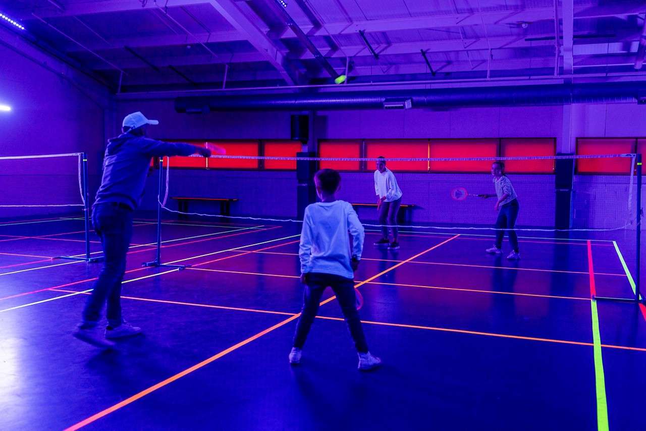 Family playing badminton with glow in the dark rackets.