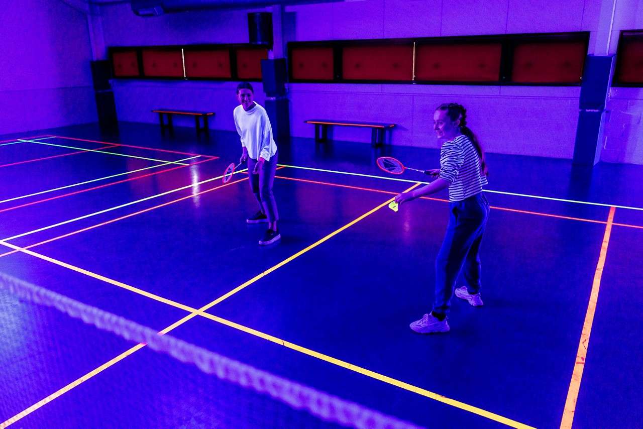 Family playing badminton with glow in the dark rackets.