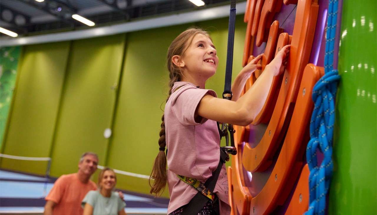 Young girl scaling an indoor climbing wall