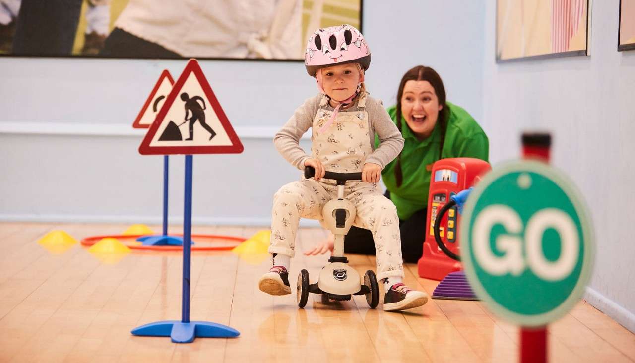 Young girl learning to use a scooter