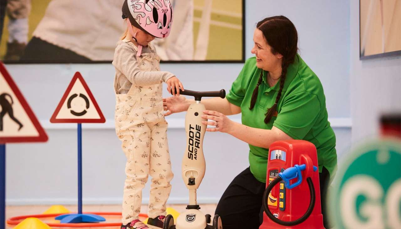 Young girl learning to use a scooter