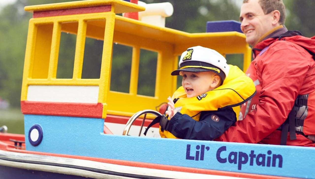 A young boy steering a colourful boat