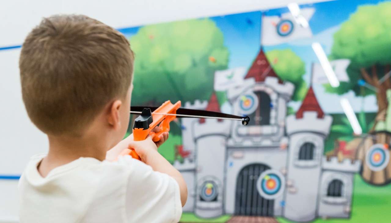 Young boy aiming a Mini Crossbow at a target