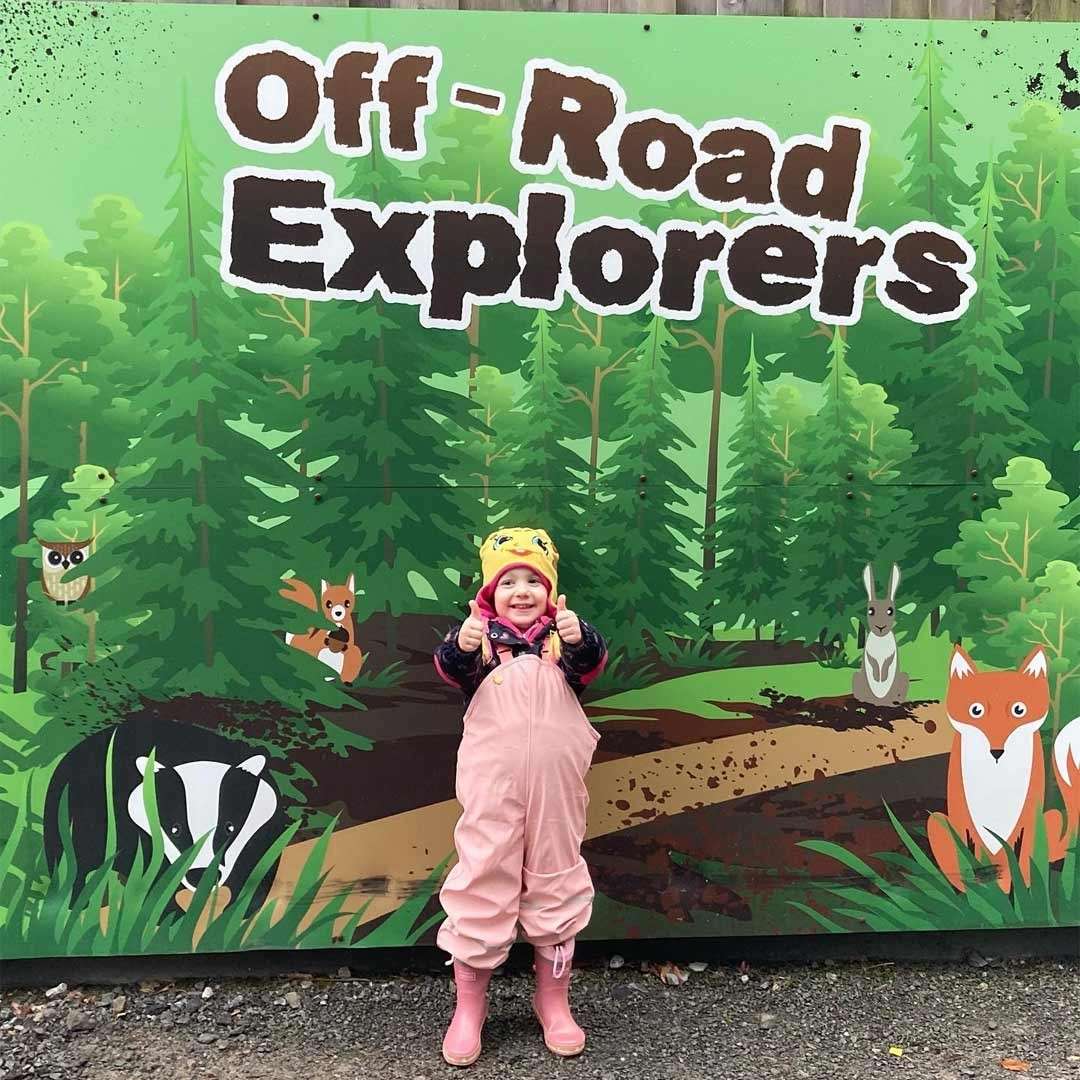 Young girl standing in front of image of the forest.