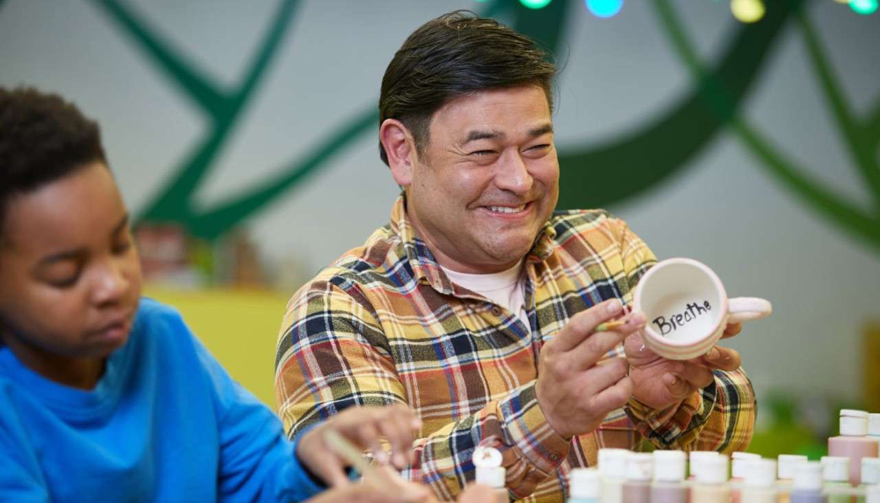 Man and young boy painting ceramic cups.