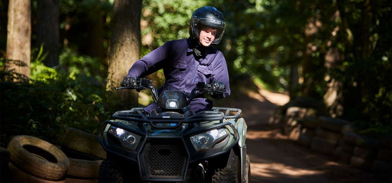 Person riding a quad bike through the forest. 