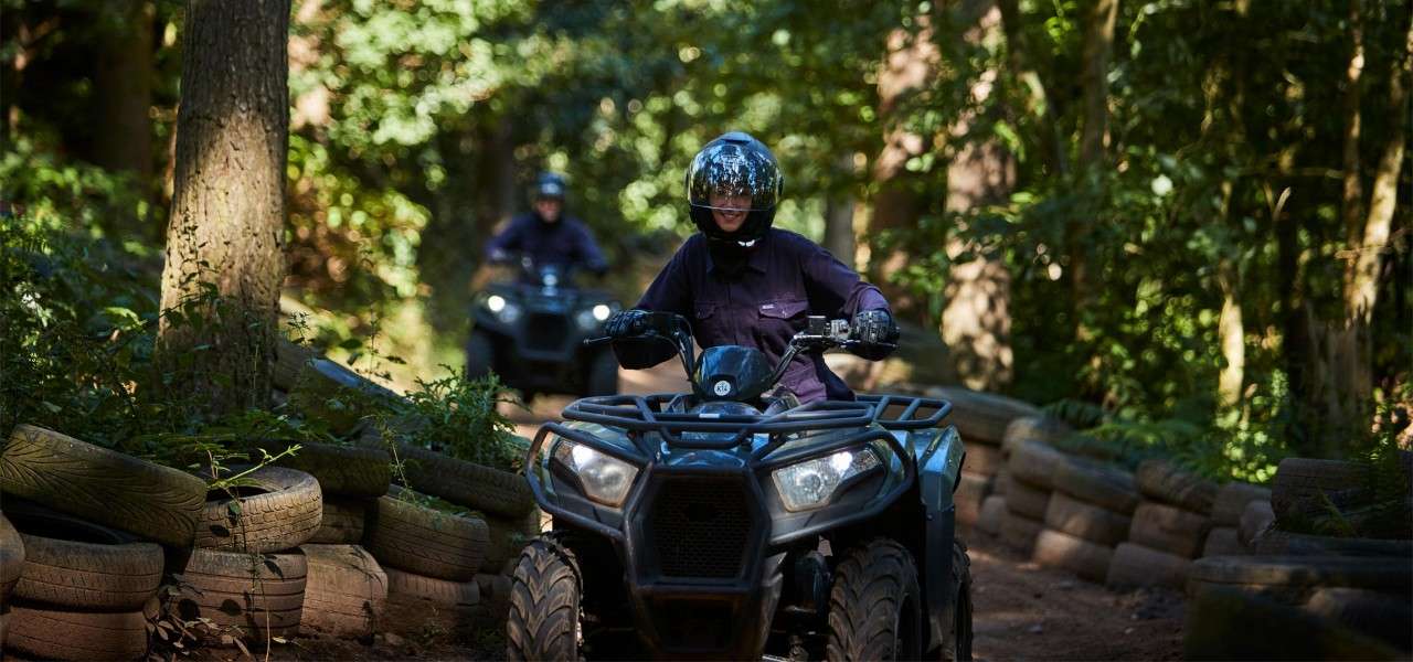 Person riding a quad bike through the forest. 