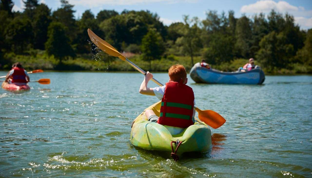 Young boy sitting on a Single Kayak floating on the lake.
