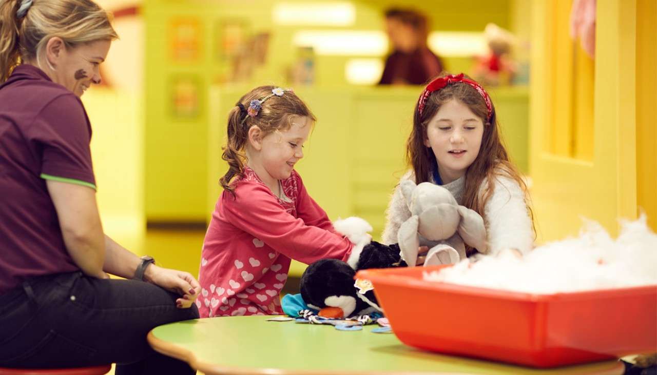 Two young girls making teddy bears.
