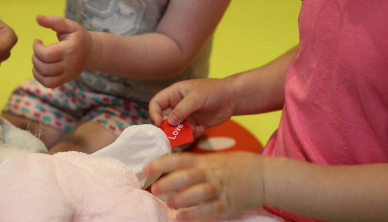 Two young girls making teddy bears.