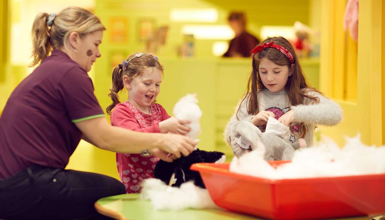 Two young girls stuffing teddy bears.