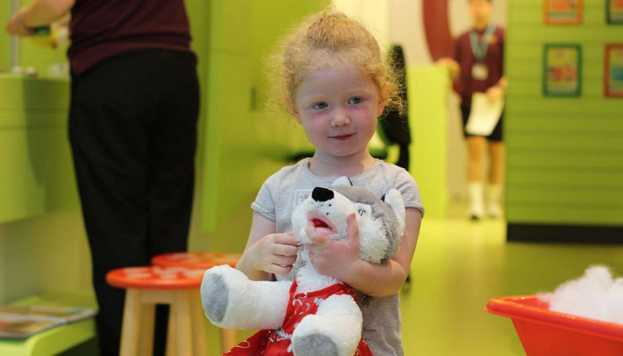 Young girl holding her newly created teddy bear.