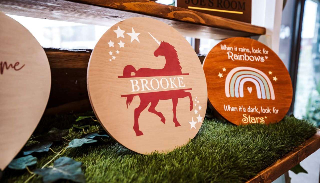 Two wooden plaques decorated with rainbows and unicorns.