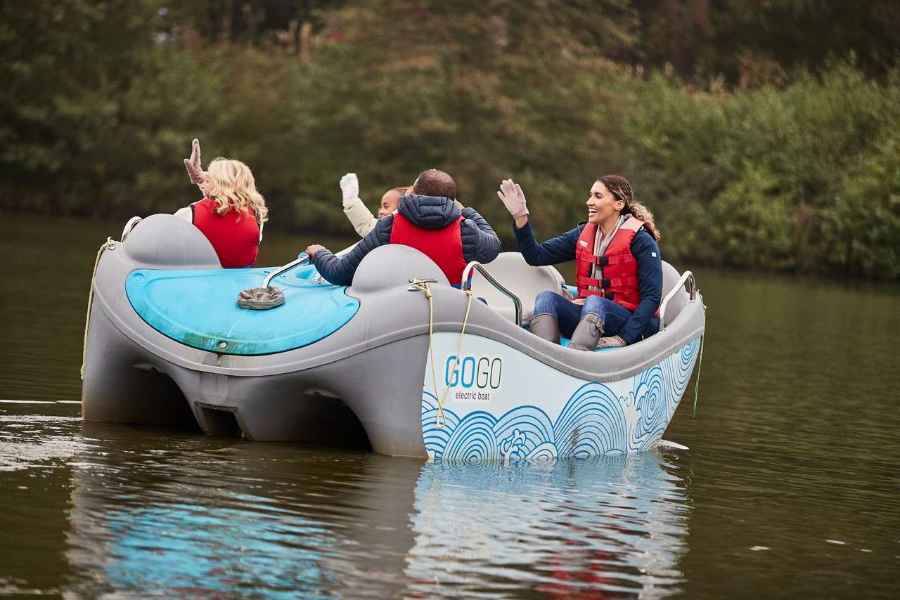 A family waving from their electric boat.