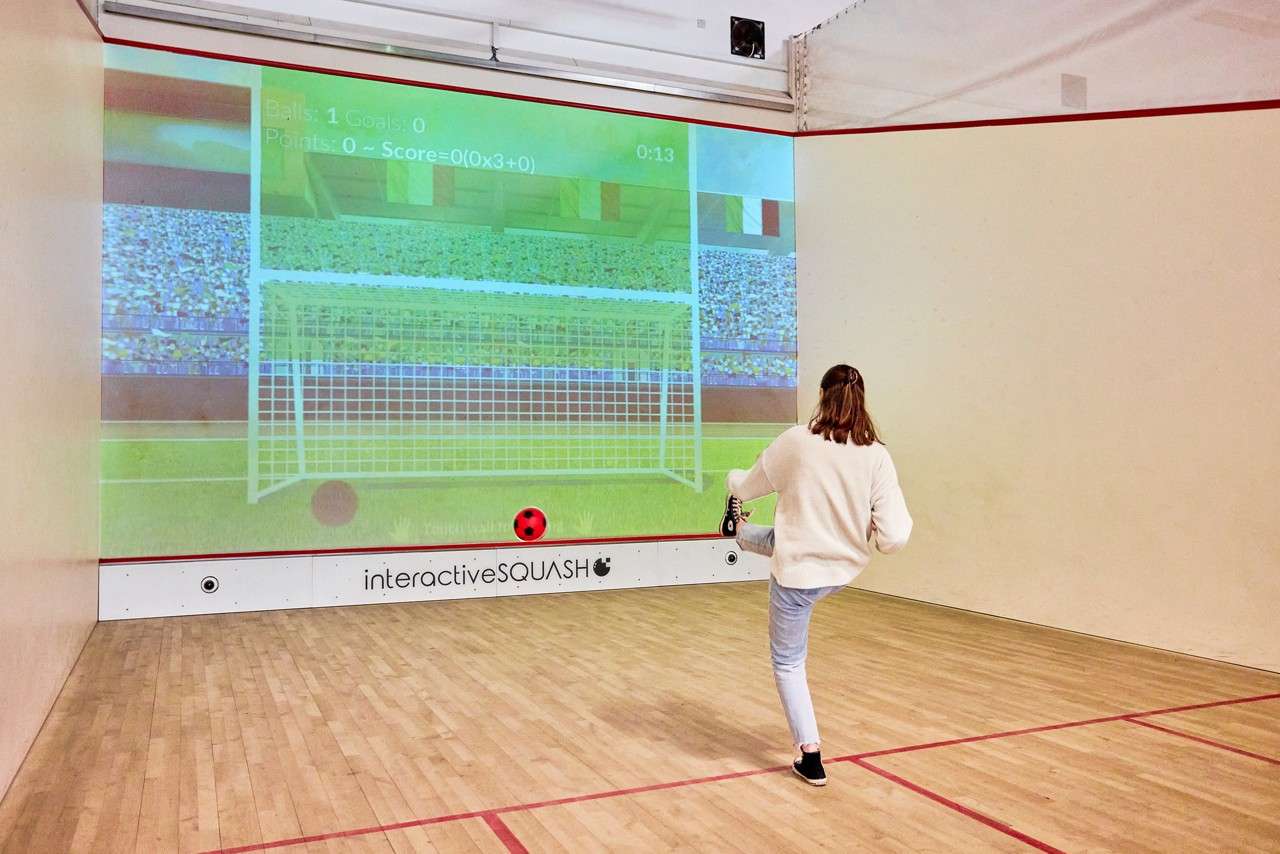 A girl kicking a ball into an interactive goal