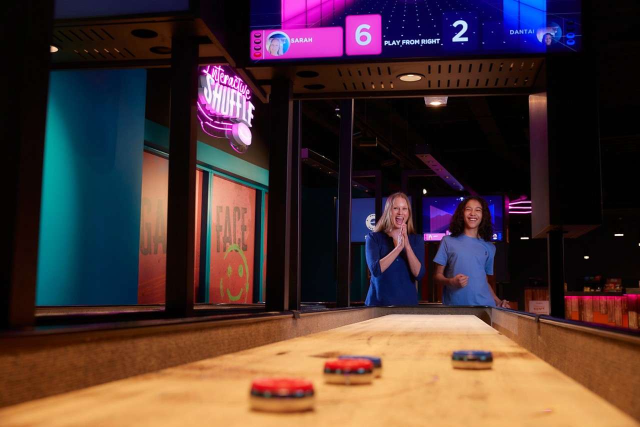 Two girls watching their shuffleboard puts in anticipation