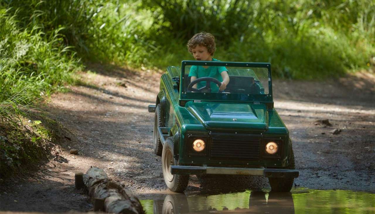 A little boy riding through a muddy puddle
