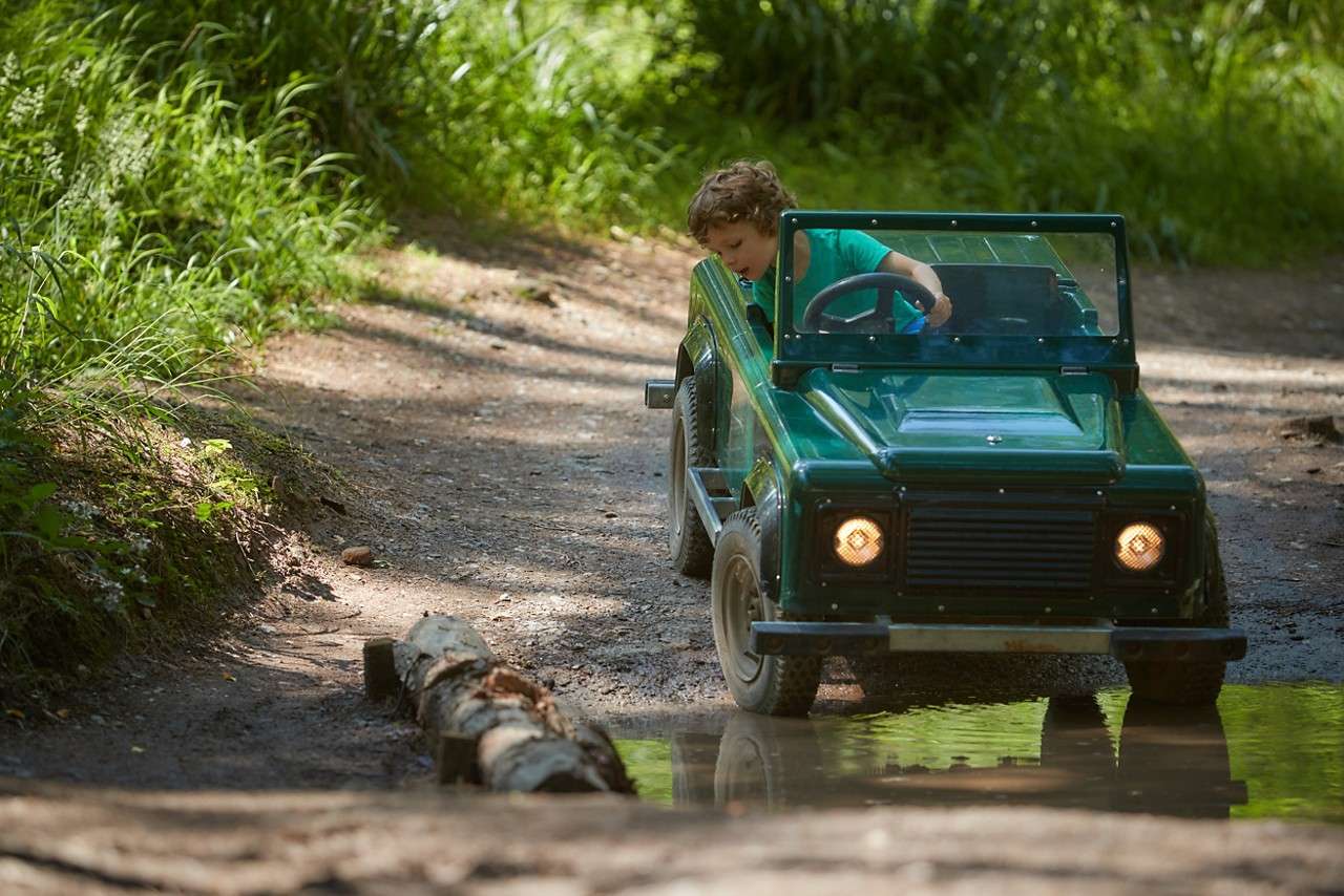 A little boy riding through a muddy puddle