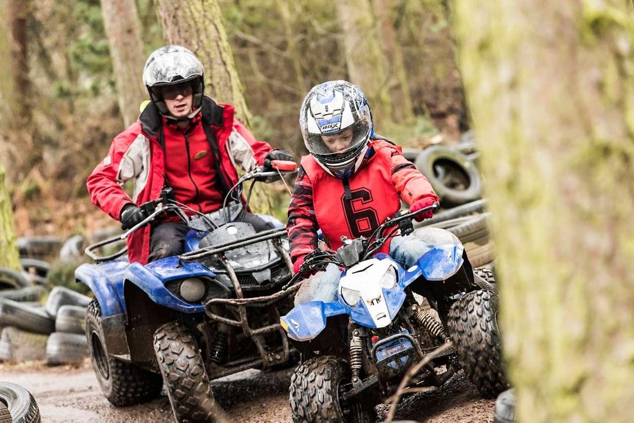 A boy on a quad bike in a red suit
