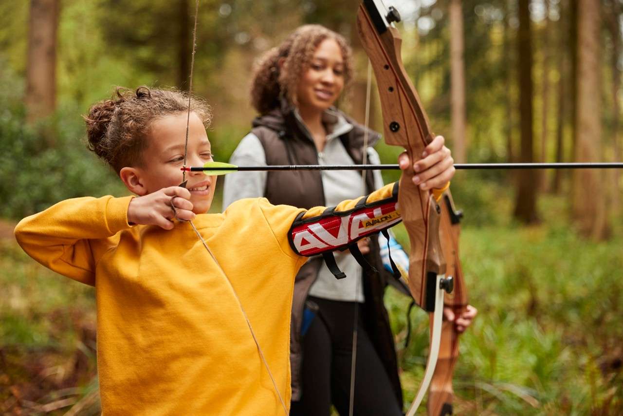 A boy focusing and aiming his arrow. 