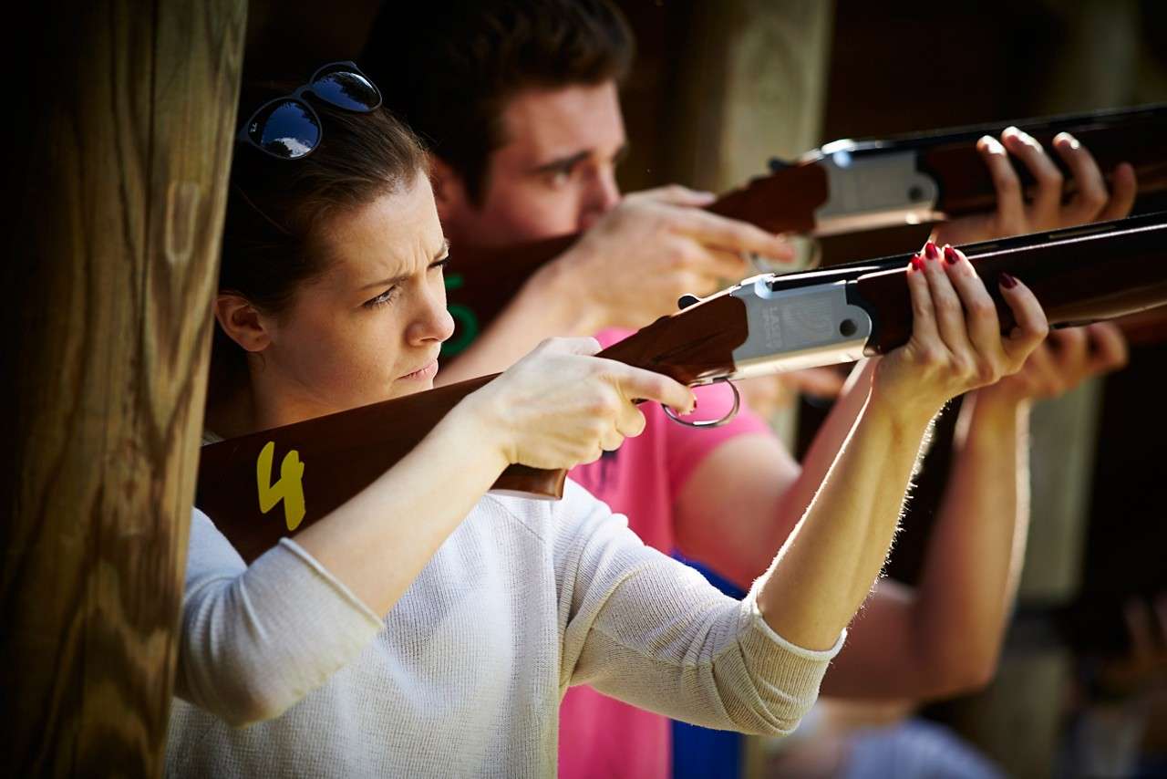 Two people taking aim in laser clay shoot out