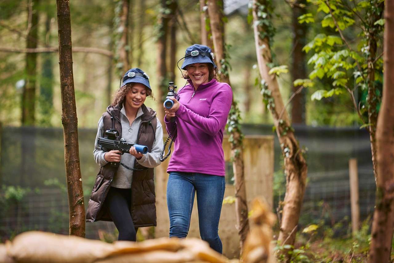 Mum and daughter in the woodland with laser guns