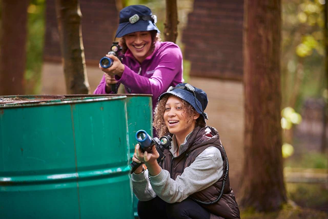 A girl hiding behind a barrel getting ready to shoot her laser