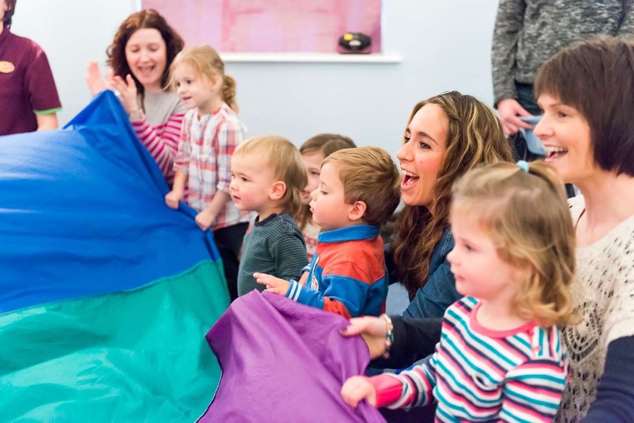 Children in a circle playing with a parachute
