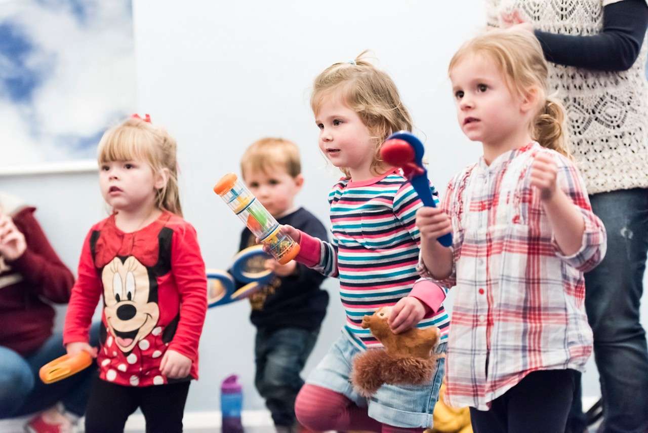 Children stood up shaking instruments