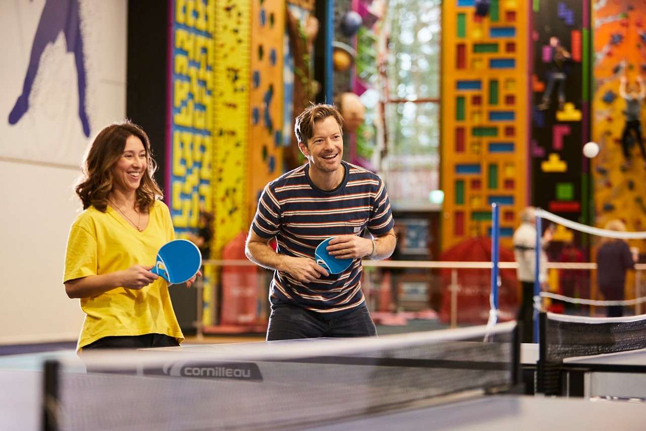 Two adults playing doubles table tennis