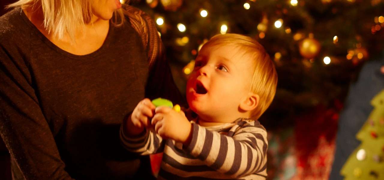 Young boy holding a toy surrounded by twinkling Christmas lights.