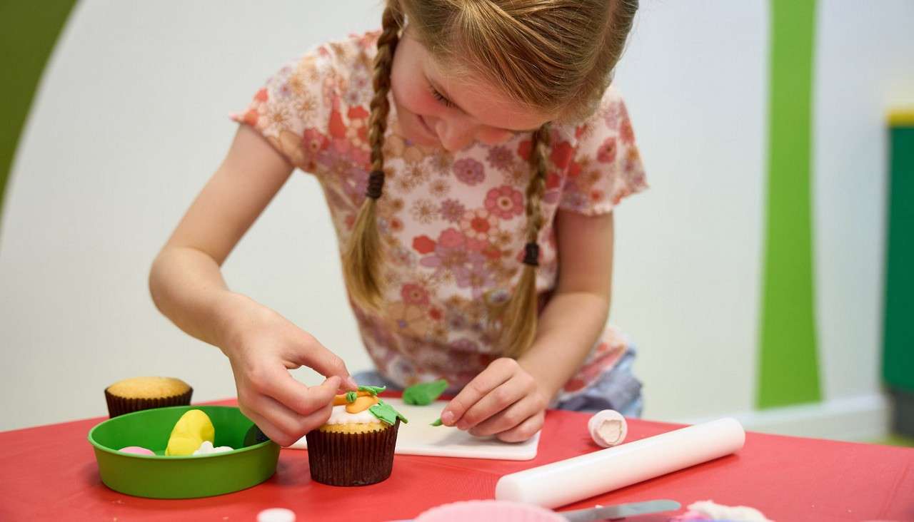 Young girl decorating a cupcake.